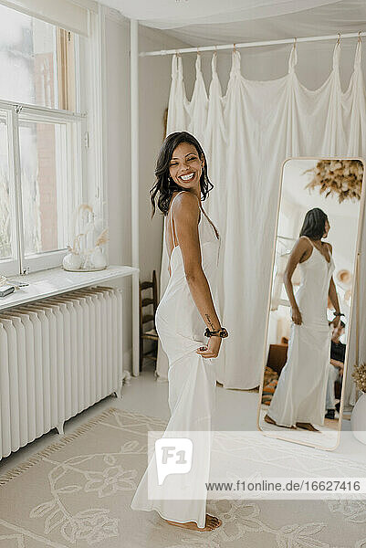 Reflection of smiling young bride standing at home