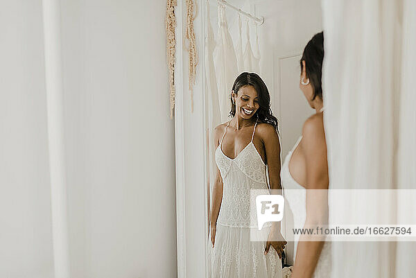 Lächelnde Braut schaut in den Spiegel  während sie zu Hause steht
