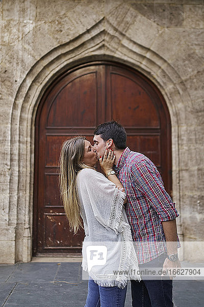 Couple kissing while standing against arch entrance