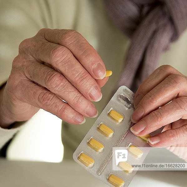 Hände einer älteren Frau mit Tabletten