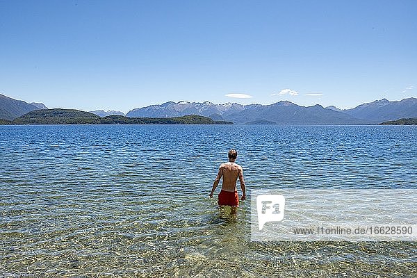 Young man bathes in the lake  Lake Manapouri  Frasers Beach  Manapouri  South Island  New Zealand  Oceania