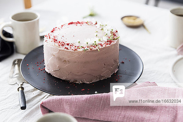 A strawberry cream cake on table laid for coffee