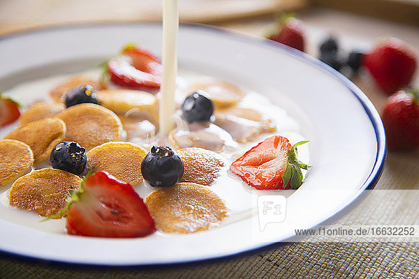 Minipancakes cereal in a bowl with milk and fruit