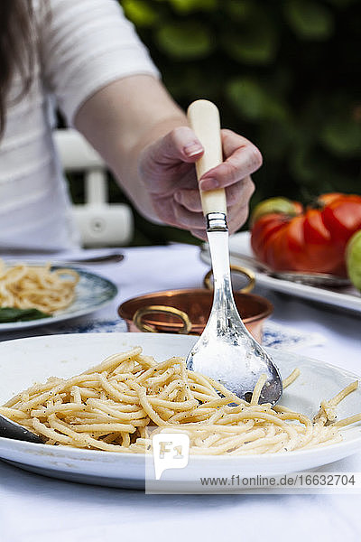 A platter of pasta cacio e pepe being served (pasta with cheese and pepper) an an outdoor table