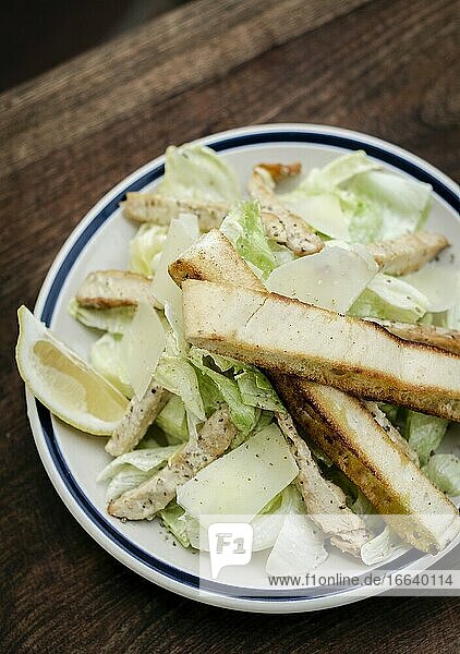 Einfacher gesunder orgaanischer Hühner-Caesar-Salat auf Holztisch.