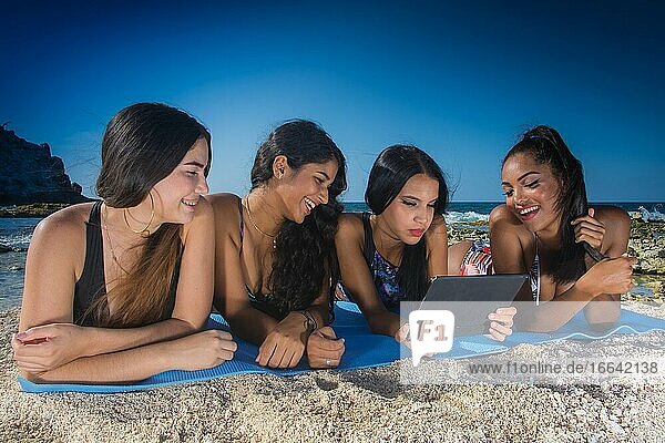 Vier glückliche Freundinnen in Sommerkleidung am Strand.