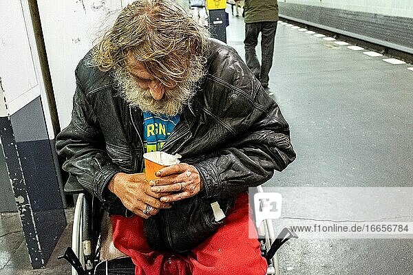 Berlin  Deutschland. Älterer erwachsener obdachloser Mann im Rollstuhl bettelt um ein paar Krümel Geld in der U-Bahn-Station Schonleinstraße.