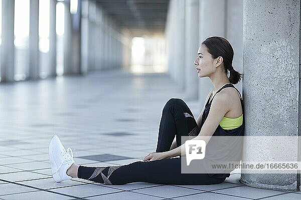 Junge japanische Frau  die beim Joggen eine Pause macht