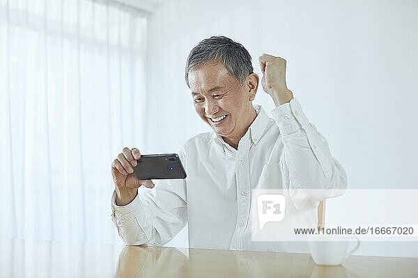 Japanischer Mann mittleren Alters  der im Zimmer lächelt