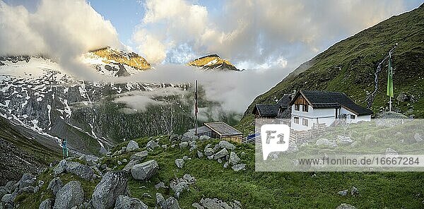 Hiker looks at mountain peaks with last sunlight  Furtschaglhaus  mountain landscape with clouds  Berliner Höhenweg  Zillertal Alps  Zillertal  Tyrol  Austria  Europe