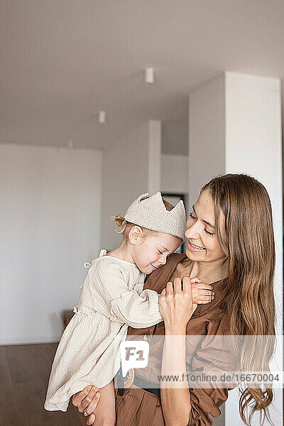 Mutter tanzt und kuschelt ihr kleines Mädchen auf Händen in einem neuen leeren Haus.