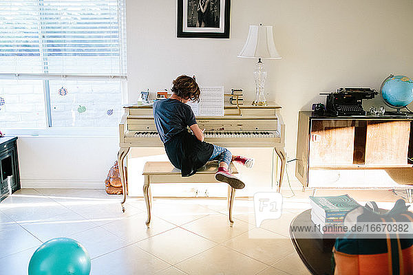 Teenager-Mädchen sitzt auf einer Klavierbank und spielt unangemessen Klavier