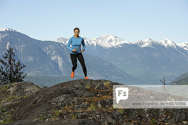 Frontansicht einer starken Sportlerin  die beim Fitnesstraining auf dem Lande gegen einen verschneiten Bergkamm läuft