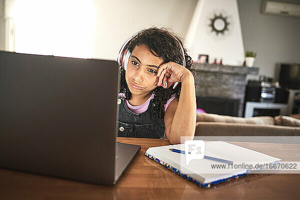 Nahaufnahme eines gelangweilten Mädchens  das zu Hause am Laptop seine Hausaufgaben macht
