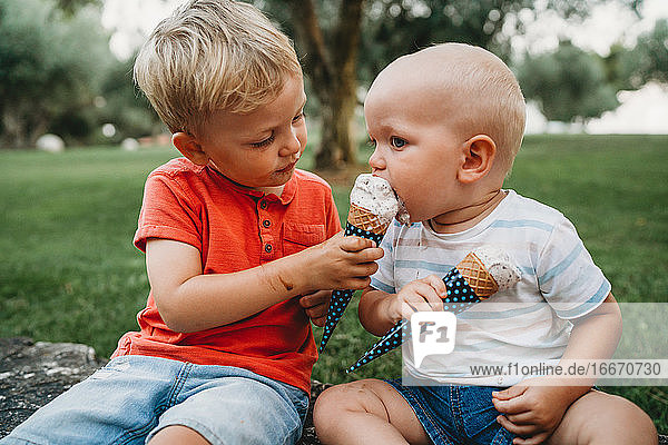 Big brother sharing his ice cream cone with his baby sibling