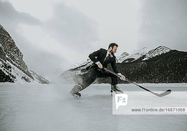 hockey player on frozen lake in suit stops fast and sprays ice
