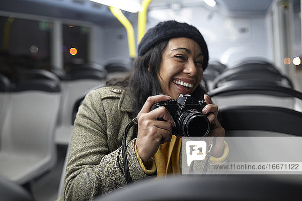Lächelnde Frau beim Fotografieren in einem öffentlichen Verkehrsmittel