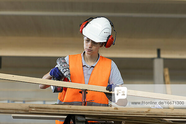 Junge Frau arbeitet in einer Werkstatt als Handwerkerin