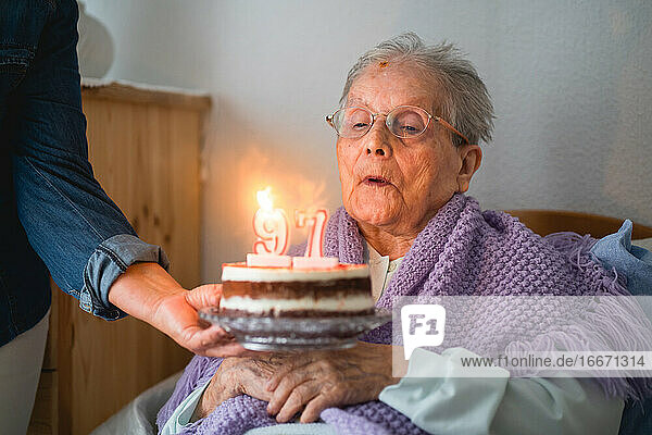 Alte Frau bläst mit ihrer Tochter die Kerzen auf der Torte zu seinem 96. Geburtstag aus