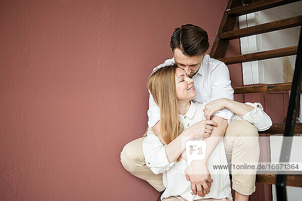 Männlich und weiblich umarmen einander mit Liebe sitzen auf Treppe zu Hause