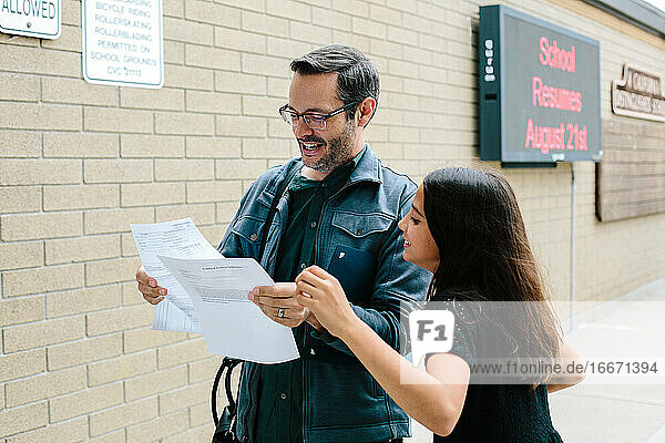 Father and daughter smile while looking at report card together