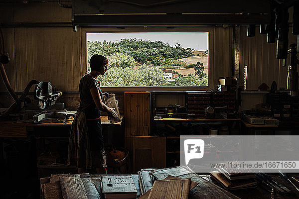 Frau bei der Arbeit in einer Werkstatt mit Blick aufs Land