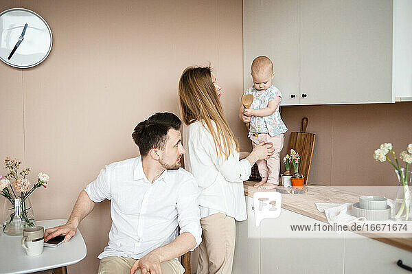 Eltern unterhalten sich während des Frühstücks mit ihrem kleinen Kind in der Küche.