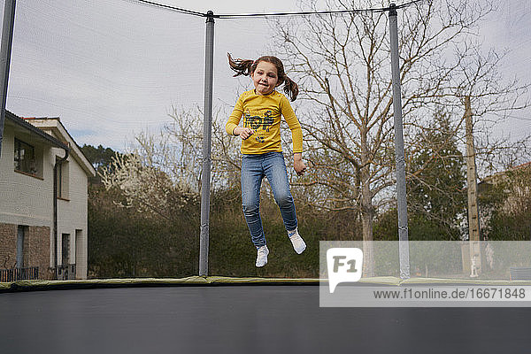 Mädchen springt auf Trampolin im Hof