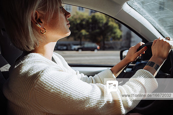Innenansicht einer blonden  kaukasischen Frau  die ein Auto fährt