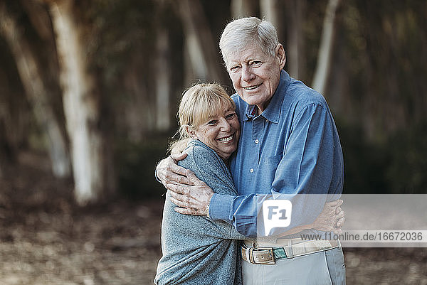 Porträt eines erwachsenen Paares im Ruhestand  das sich im Wald umarmt