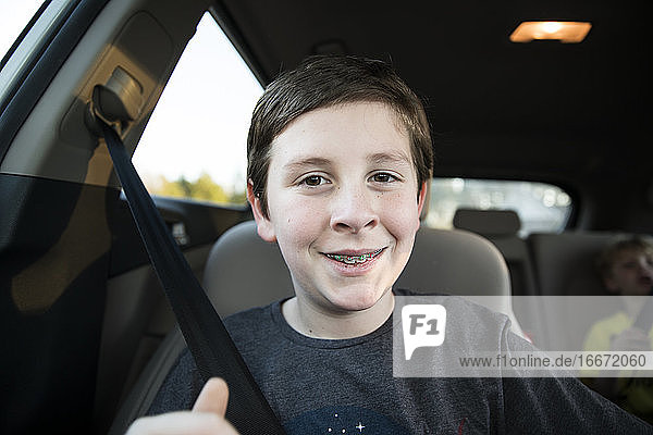 Close Up of Smiling Teen Boy With Braces Sitting in Car