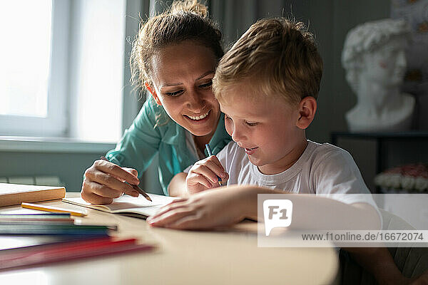 Cheerful woman drawing with boy