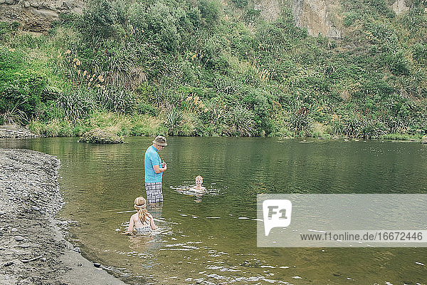 Familie an einer malerischen Flussstelle beim Spielen im Wasser