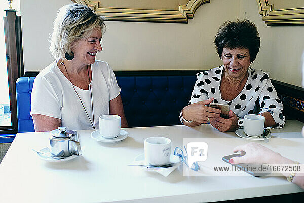 Lächelnde Frauen beim Kaffeetrinken mit ihren Freunden