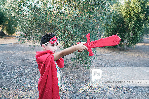 ein als roter Superheld verkleidetes Kind richtet sein Schwert auf die Geister