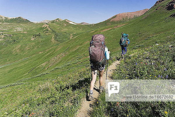 Rückansicht von Wanderinnen beim Bergsteigen an einem sonnigen Tag