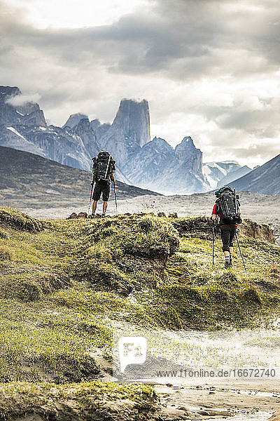 Zwei Bergsteiger wandern über einen dramatischen Bergpass.
