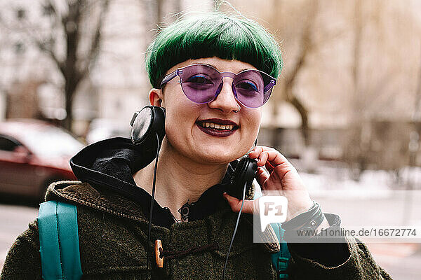 Porträt eines glücklichen nicht-binären Hipsters auf einer Straße in der Stadt
