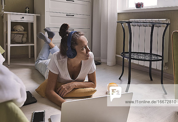 Junge Frau am Fenster liegend zu Hause mit Laptop