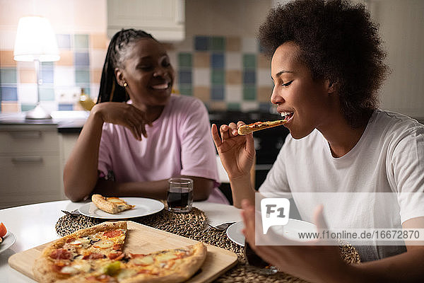 Schwarze Frau isst Pizza in der Nähe eines Freundes