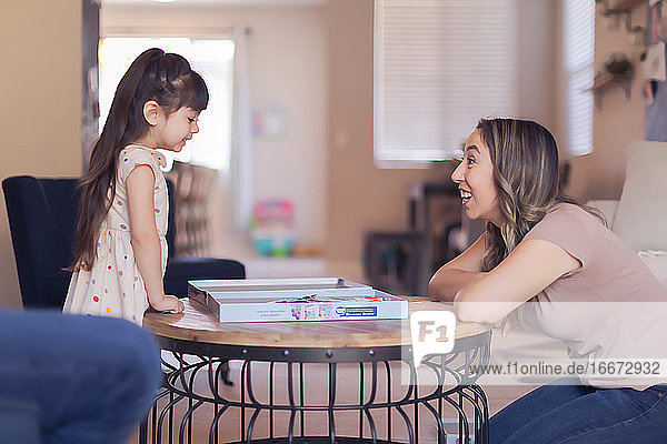 Mother looking at daughter  both excited about playing a game at home.