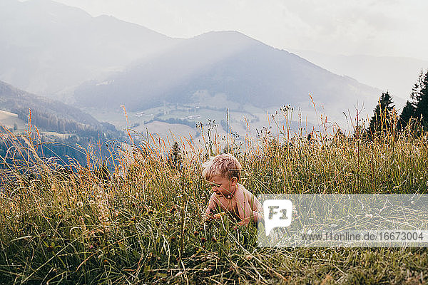 Kind versteckt sich im Sommer im Gras in den Bergen