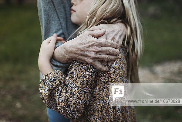 Detailaufnahme eines jungen Mädchens  das von einer älteren Großmutter umarmt wird