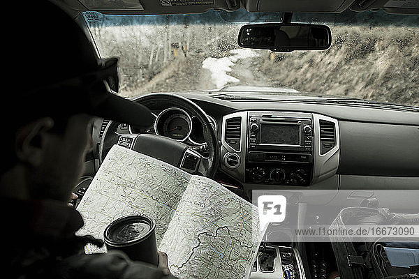Mann beim Lesen einer Karte während der Fahrt im Auto