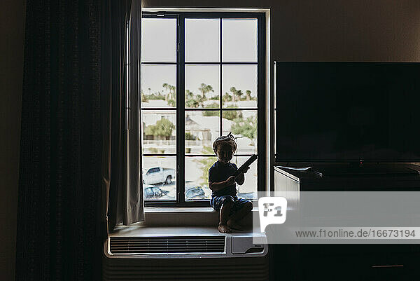 Kleiner Junge sitzt im Fenster eines Hotelzimmers in Palm Springs