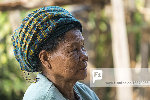 Nahaufnahme einer nachdenklichen älteren birmanischen Frau mit Kopfbedeckung  die wegschaut  Hsipaw  Myanmar