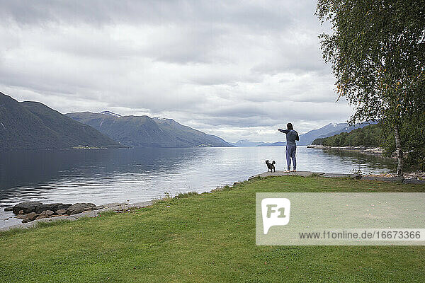 Ein Mann und sein kleiner Hund schauen über einen Fjord in Norwegen