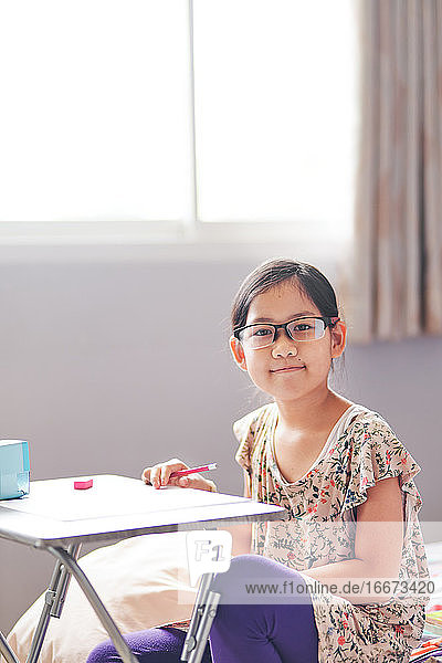 Porträt eines Mädchens mit ihrem Tisch voller Hausaufgaben