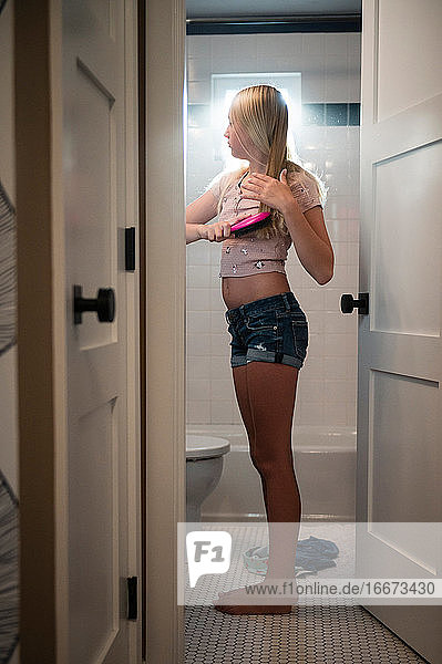 Teenager-Mädchen in Freizeitkleidung im Bad stehend  Haare bürstend