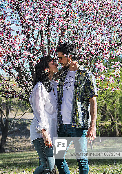 young couple in park with pink flowers